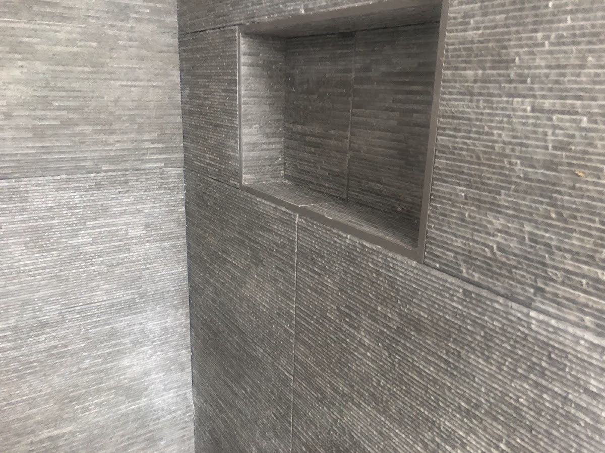 Dark split-face stone shower wall tiled by A.K Tiling