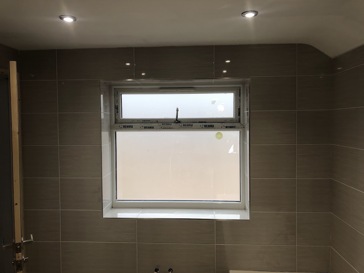 Taupe large-format bathroom walls with recessed spotlights